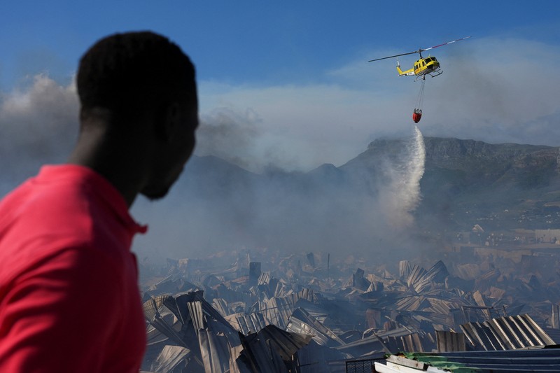 Seorang petugas pemadam kebakaran berdiri di samping kobaran api yang masih berlangsung di daerah Franschhoek, Cape Town, Afrika Selatan, 21 Januari 2026. (REUTERS/Esa Alexander)