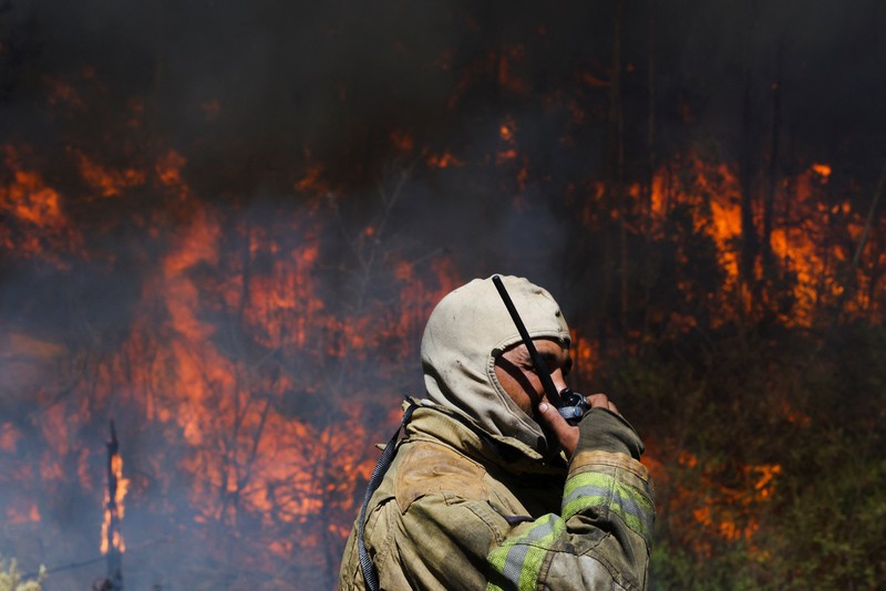 Seorang petugas pemadam kebakaran berdiri di samping kobaran api yang masih berlangsung di daerah Franschhoek, Cape Town, Afrika Selatan, 21 Januari 2026. (REUTERS/Esa Alexander)