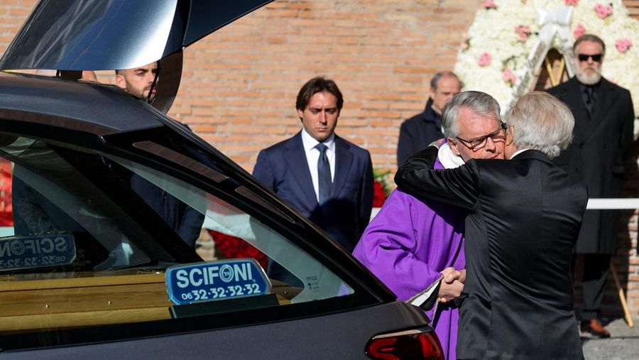 Anthony Souza, anak baptis mendiang perancang busana Valentino Garavani, dan para pengusung peti mati membawa peti jenazah Valentino Garavani, yang meninggal pada usia 93 tahun, di luar Basilika Santa Maria dari Para Malaikat dan Martir, selama upacara pemakaman, di Roma, Italia, 23 Januari 2026. (REUTERS/Yara Nardi)