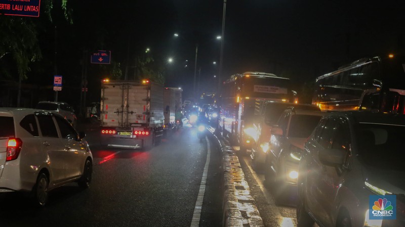 Sejumlah kendaraan terjebak kemacetan panjang di Jalan Raya HM Martono, Bekasi, Jawa Barat, akibat banjir yang merendam wilayah Jatimulya, Kamis (22/1/2026) malam. Genangan air membuat ruas jalan tersebut sempat tidak dapat dilalui kendaraan. (CNBC Indonesia/Tias Budiarto)