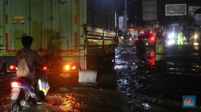 Sejumlah kendaraan terjebak kemacetan panjang di Jalan Raya HM Martono, Bekasi, Jawa Barat, akibat banjir yang merendam wilayah Jatimulya, Kamis (22/1/2026) malam. Genangan air membuat ruas jalan tersebut sempat tidak dapat dilalui kendaraan. (CNBC Indonesia/Tias Budiarto)