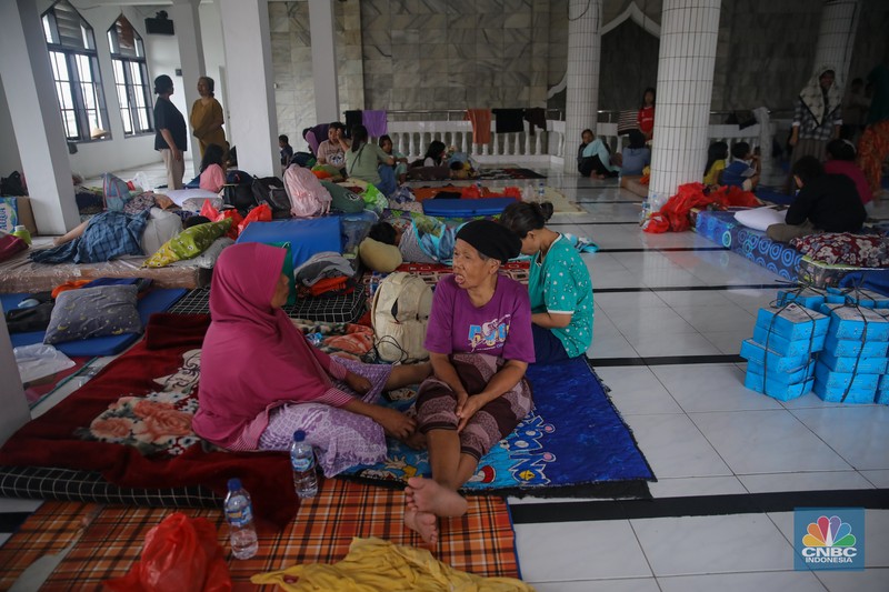Warga melintasi banjir yang melanda pemukiman penduduk di Kawasan Taman Kota, Kedaung Kali Angke, Jakarta Barat, Jumat (23/1/2026). (CNBC Indonesia/Faisal Rahman)