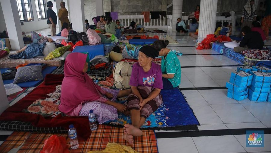Warga melintasi banjir yang melanda pemukiman penduduk di Kawasan Taman Kota, Kedaung Kali Angke, Jakarta Barat, Jumat (23/1/2026). (CNBC Indonesia/Faisal Rahman)