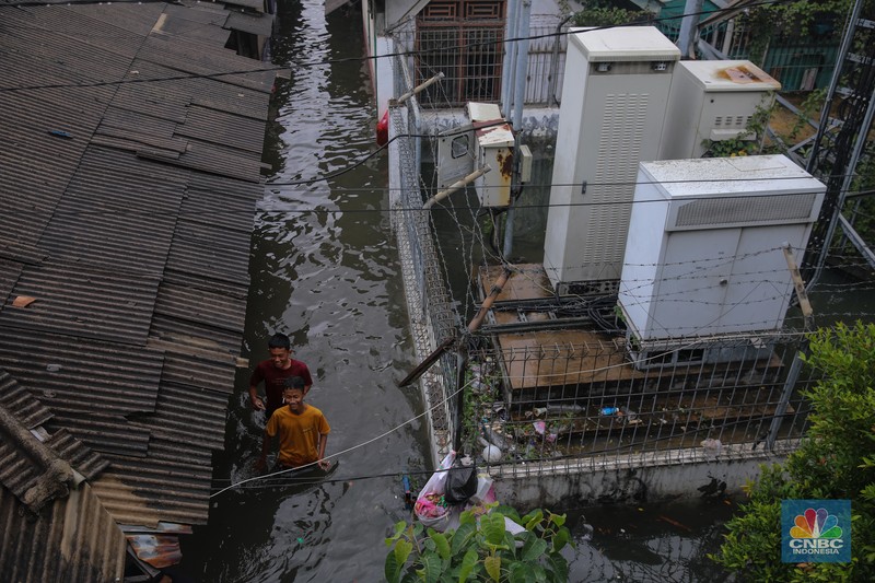 Warga melintasi banjir yang melanda pemukiman penduduk di Kawasan Taman Kota, Kedaung Kali Angke, Jakarta Barat, Jumat (23/1/2026). (CNBC Indonesia/Faisal Rahman)