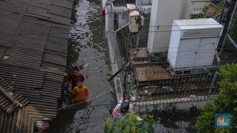 Warga melintasi banjir yang melanda pemukiman penduduk di Kawasan Taman Kota, Kedaung Kali Angke, Jakarta Barat, Jumat (23/1/2026). (CNBC Indonesia/Faisal Rahman)