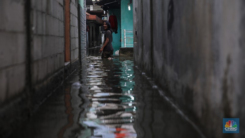 Warga melintasi banjir yang melanda pemukiman penduduk di Kawasan Taman Kota, Kedaung Kali Angke, Jakarta Barat, Jumat (23/1/2026). (CNBC Indonesia/Faisal Rahman)