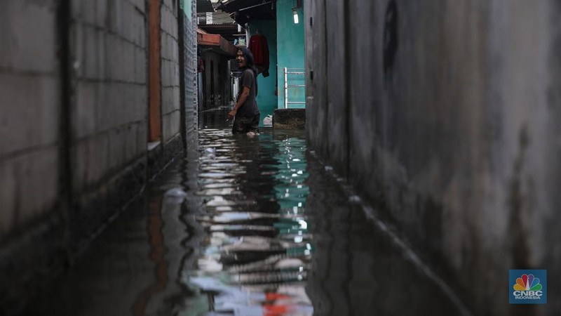 Warga melintasi banjir yang melanda pemukiman penduduk di Kawasan Taman Kota, Kedaung Kali Angke, Jakarta Barat, Jumat (23/1/2026). (CNBC Indonesia/Faisal Rahman)