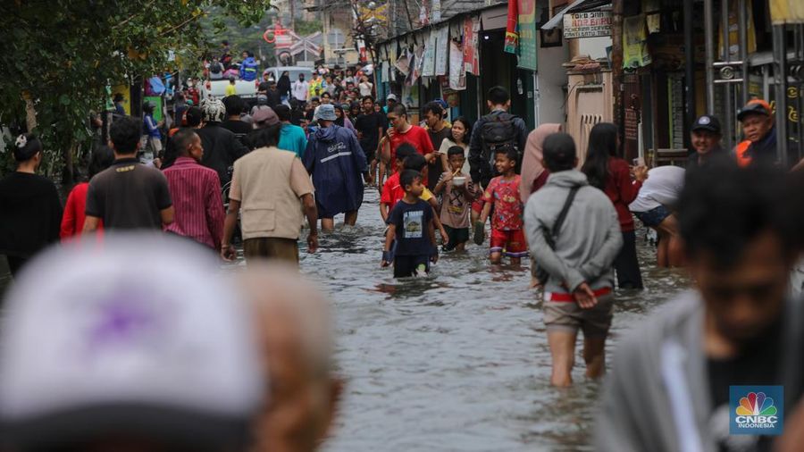 Warga melintasi banjir yang melanda pemukiman penduduk di Kawasan Taman Kota, Kedaung Kali Angke, Jakarta Barat, Jumat (23/1/2026). (CNBC Indonesia/Faisal Rahman)