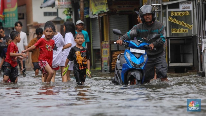 Warga melintasi banjir yang melanda pemukiman penduduk di Kawasan Taman Kota, Kedaung Kali Angke, Jakarta Barat, Jumat (23/1/2026). (CNBC Indonesia/Faisal Rahman)