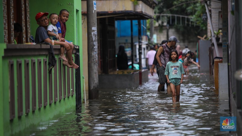 Warga melintasi banjir yang melanda pemukiman penduduk di Kawasan Taman Kota, Kedaung Kali Angke, Jakarta Barat, Jumat (23/1/2026). (CNBC Indonesia/Faisal Rahman)
