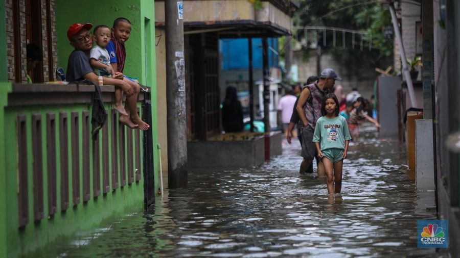 Warga melintasi banjir yang melanda pemukiman penduduk di Kawasan Taman Kota, Kedaung Kali Angke, Jakarta Barat, Jumat (23/1/2026). (CNBC Indonesia/Faisal Rahman)