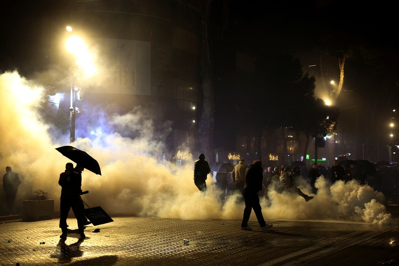 Seorang demonstran menyalakan kembang api di luar kantor Perdana Menteri selama protes anti-pemerintah yang dipicu oleh penyelidikan korupsi terhadap Wakil Perdana Menteri Belinda Balluku, di Tirana, Albania, 24 Januari 2026. (REUTERS/Florion Goga)