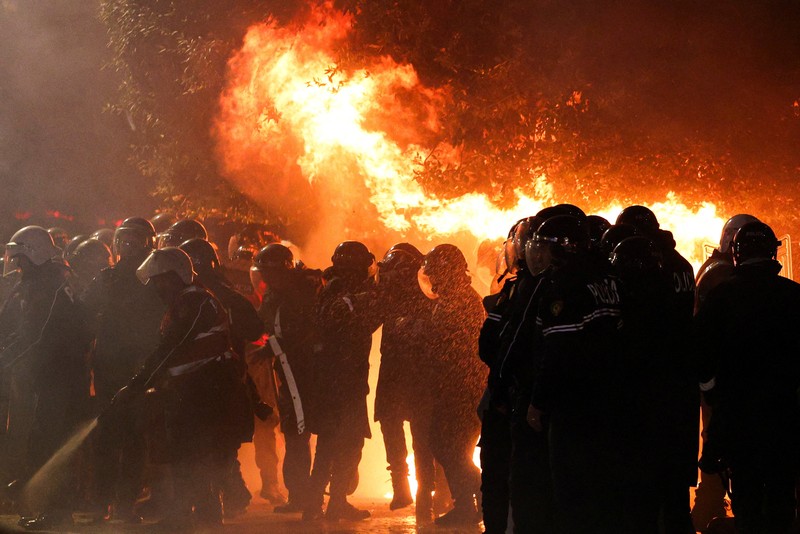 Seorang demonstran menyalakan kembang api di luar kantor Perdana Menteri selama protes anti-pemerintah yang dipicu oleh penyelidikan korupsi terhadap Wakil Perdana Menteri Belinda Balluku, di Tirana, Albania, 24 Januari 2026. (REUTERS/Florion Goga)