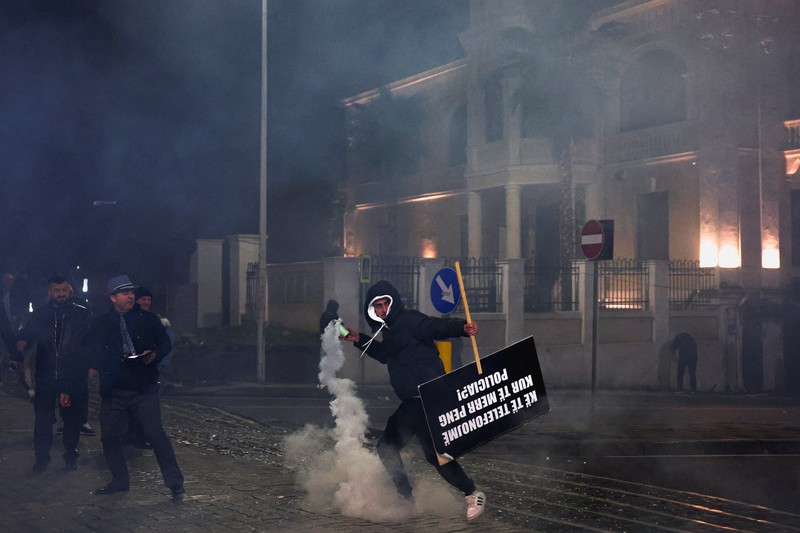 Seorang demonstran menyalakan kembang api di luar kantor Perdana Menteri selama protes anti-pemerintah yang dipicu oleh penyelidikan korupsi terhadap Wakil Perdana Menteri Belinda Balluku, di Tirana, Albania, 24 Januari 2026. (REUTERS/Florion Goga)