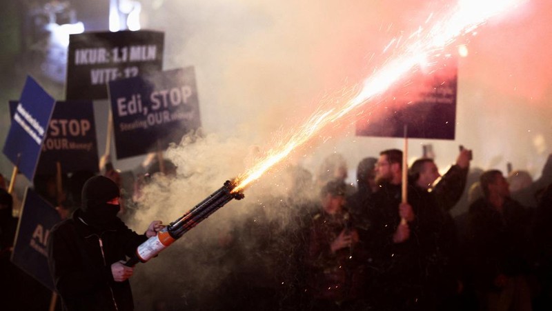 Seorang demonstran menyalakan kembang api di luar kantor Perdana Menteri selama protes anti-pemerintah yang dipicu oleh penyelidikan korupsi terhadap Wakil Perdana Menteri Belinda Balluku, di Tirana, Albania, 24 Januari 2026. (REUTERS/Florion Goga)