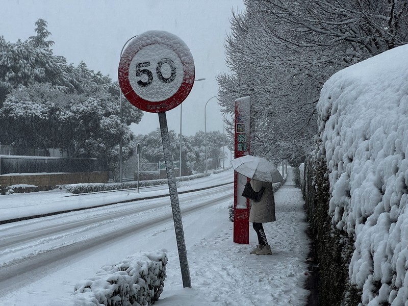 Orang-orang berjalan di jalanan yang tertutup salju saat badai Kristin melanda beberapa bagian Spanyol dan Portugal, di Galapagos, pinggiran Madrid, Spanyol, Rabu (28/1/2026). (REUTERS/Silvio Castellanos)