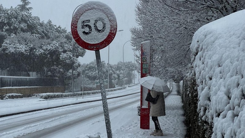 Orang-orang berjalan di jalanan yang tertutup salju saat badai Kristin melanda beberapa bagian Spanyol dan Portugal, di Galapagos, pinggiran Madrid, Spanyol, Rabu (28/1/2026). (REUTERS/Silvio Castellanos)