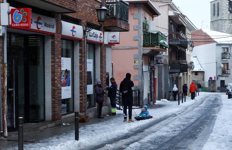 Orang-orang berjalan di jalanan yang tertutup salju saat badai Kristin melanda beberapa bagian Spanyol dan Portugal, di Galapagos, pinggiran Madrid, Spanyol, Rabu (28/1/2026). (REUTERS/Silvio Castellanos)