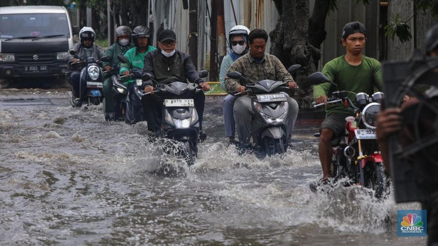 Sejumlah pengendara sepeda motor menerobos banjir yang melanda kawasan Jalan Inspeksi, Jakarta Utara, Kamis (29/1/2026). (CNBC Indonesia/Faisal Rahman)