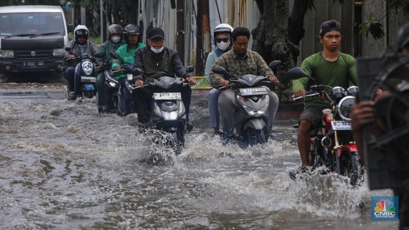 Sejumlah pengendara sepeda motor menerobos banjir yang melanda kawasan Jalan Inspeksi, Jakarta Utara, Kamis (29/1/2026). (CNBC Indonesia/Faisal Rahman)