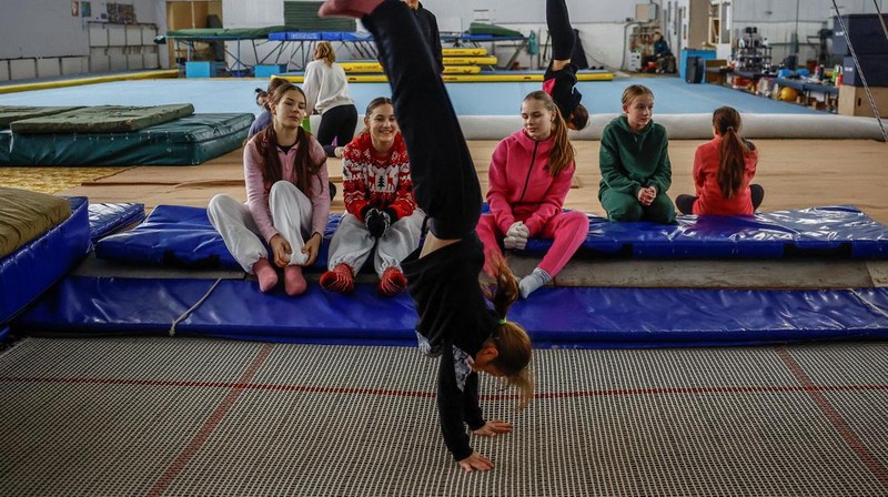 Gadis-gadis yang mengenakan kaus kaki hangat dan pakaian musim dingin berlapis-lapis mengikuti latihan kekuatan selama sesi pelatihan di aula senam di Kiev, Ukraina, Kamis (29/1/2026). (REUTERS/Alina Smutko)