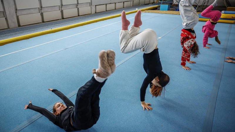 Gadis-gadis yang mengenakan kaus kaki hangat dan pakaian musim dingin berlapis-lapis mengikuti latihan kekuatan selama sesi pelatihan di aula senam di Kiev, Ukraina, Kamis (29/1/2026). (REUTERS/Alina Smutko)