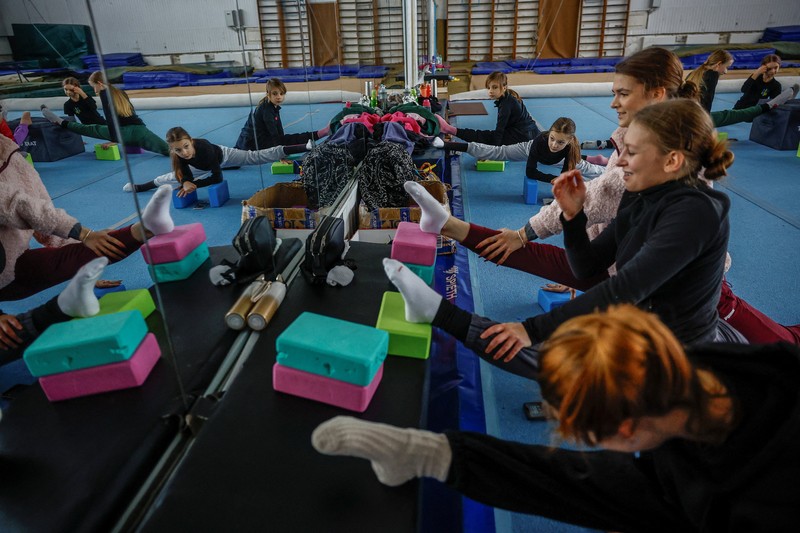 Gadis-gadis yang mengenakan kaus kaki hangat dan pakaian musim dingin berlapis-lapis mengikuti latihan kekuatan selama sesi pelatihan di aula senam di Kiev, Ukraina, Kamis (29/1/2026). (REUTERS/Alina Smutko)