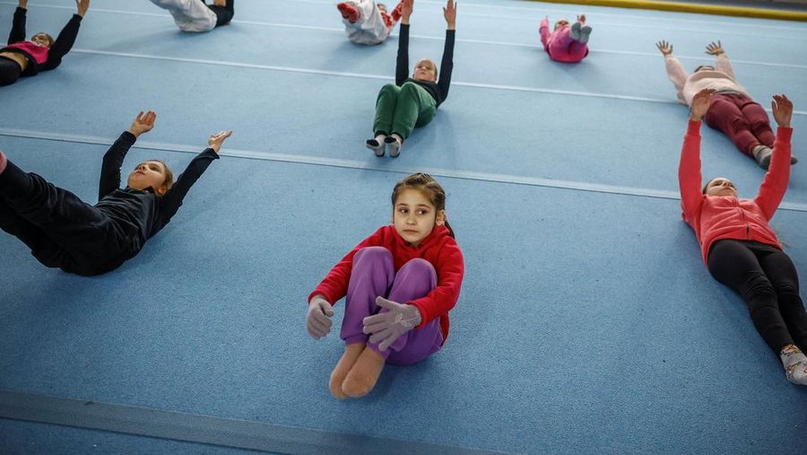 Gadis-gadis yang mengenakan kaus kaki hangat dan pakaian musim dingin berlapis-lapis mengikuti latihan kekuatan selama sesi pelatihan di aula senam di Kiev, Ukraina, Kamis (29/1/2026). (REUTERS/Alina Smutko)