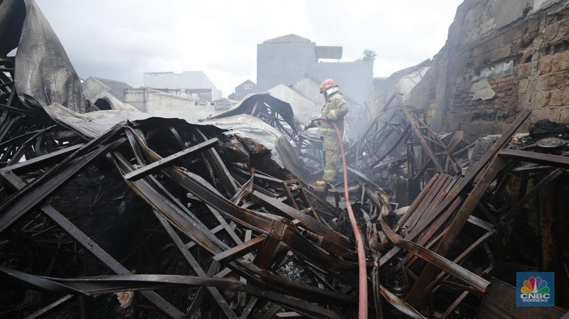 Petugas pemadam kebakaran mendinginkan sisa-sisa api yang masih menyala di Gudang dekorasi dan ruko tekstil di Jalan Pajak Raya, Cipadu, Juramangu Timur, Tangerang Selatan (Tangsel), Senin (2/1/2026). (CNBC Indonesia/Tri Susilo)