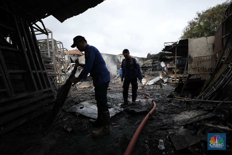 Petugas pemadam kebakaran mendinginkan sisa-sisa api yang masih menyala di Gudang dekorasi dan ruko tekstil di Jalan Pajak Raya, Cipadu, Juramangu Timur, Tangerang Selatan (Tangsel), Senin (2/1/2026). (CNBC Indonesia/Tri Susilo)