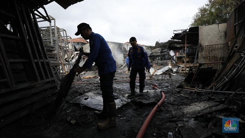 Petugas pemadam kebakaran mendinginkan sisa-sisa api yang masih menyala di Gudang dekorasi dan ruko tekstil di Jalan Pajak Raya, Cipadu, Juramangu Timur, Tangerang Selatan (Tangsel), Senin (2/1/2026). (CNBC Indonesia/Tri Susilo)
