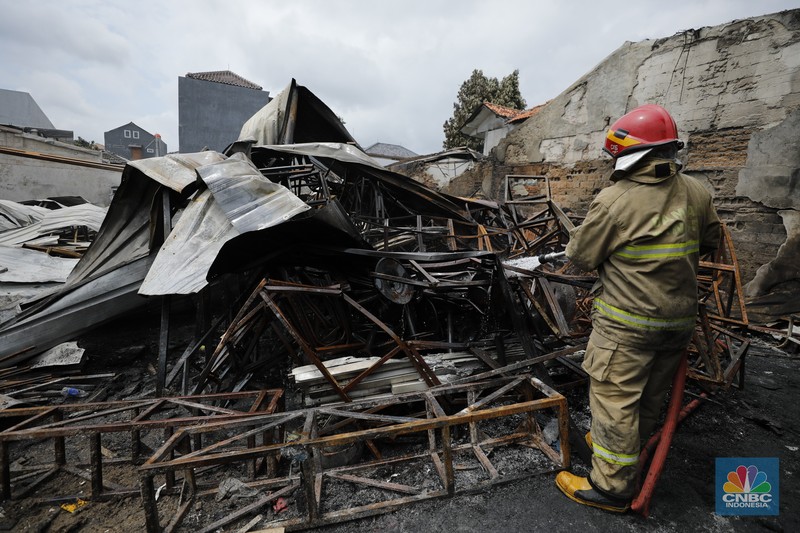 Petugas pemadam kebakaran mendinginkan sisa-sisa api yang masih menyala di Gudang dekorasi dan ruko tekstil di Jalan Pajak Raya, Cipadu, Juramangu Timur, Tangerang Selatan (Tangsel), Senin (2/1/2026). (CNBC Indonesia/Tri Susilo)