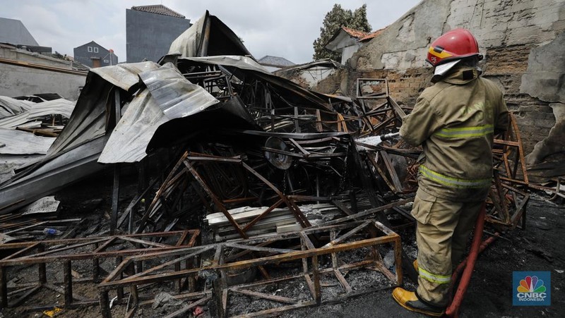 Petugas pemadam kebakaran mendinginkan sisa-sisa api yang masih menyala di Gudang dekorasi dan ruko tekstil di Jalan Pajak Raya, Cipadu, Juramangu Timur, Tangerang Selatan (Tangsel), Senin (2/1/2026). (CNBC Indonesia/Tri Susilo)