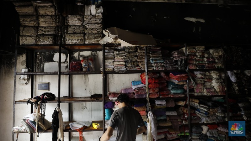 Petugas pemadam kebakaran mendinginkan sisa-sisa api yang masih menyala di Gudang dekorasi dan ruko tekstil di Jalan Pajak Raya, Cipadu, Juramangu Timur, Tangerang Selatan (Tangsel), Senin (2/1/2026). (CNBC Indonesia/Tri Susilo)