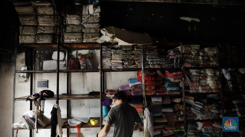 Petugas pemadam kebakaran mendinginkan sisa-sisa api yang masih menyala di Gudang dekorasi dan ruko tekstil di Jalan Pajak Raya, Cipadu, Juramangu Timur, Tangerang Selatan (Tangsel), Senin (2/1/2026). (CNBC Indonesia/Tri Susilo)