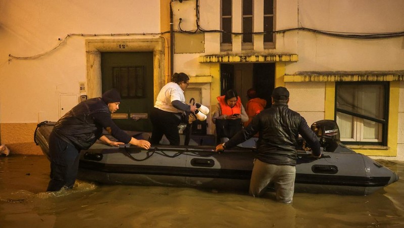 Seorang pria menerobos genangan air untuk mencapai rumahnya saat badai Leo membanjiri jalanan Alcacer do Sal, Portugal, 4 Februari 2026. (REUTERS/Pedro Nunes)