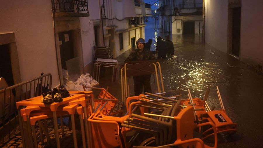 Seorang pria menerobos genangan air untuk mencapai rumahnya saat badai Leo membanjiri jalanan Alcacer do Sal, Portugal, 4 Februari 2026. (REUTERS/Pedro Nunes)