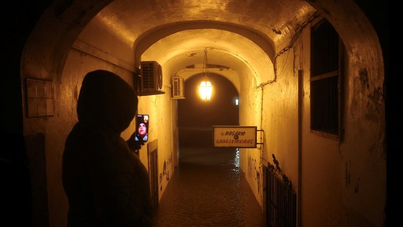 Seorang pria menerobos genangan air untuk mencapai rumahnya saat badai Leo membanjiri jalanan Alcacer do Sal, Portugal, 4 Februari 2026. (REUTERS/Pedro Nunes)