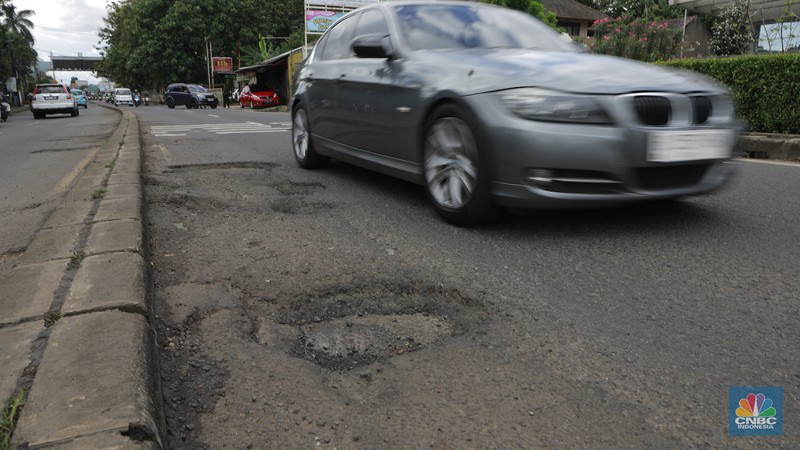 Pengendara mobil roda empat menghindari lobang di Jl raya Moh Toha, Tangeran Selatan, Jumat (6/2/2026). (CNBC Indonesia/Muhammad Sabki)