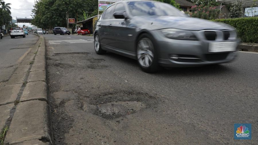 Pengendara mobil roda empat menghindari lobang di Jl raya Moh Toha, Tangeran Selatan, Jumat (6/2/2026). (CNBC Indonesia/Muhammad Sabki)