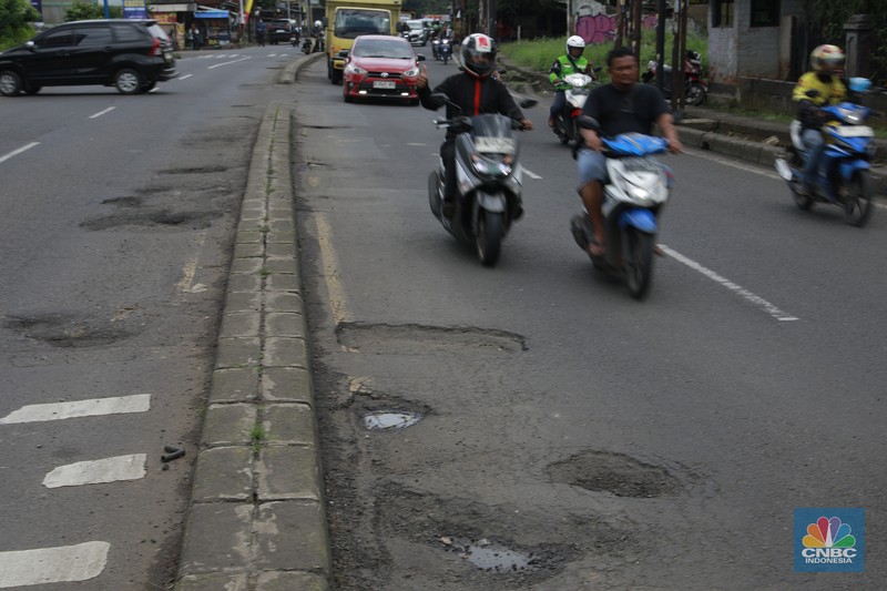 Pengendara mobil roda empat menghindari lobang di Jl raya Moh Toha, Tangeran Selatan, Jumat (6/2/2026). (CNBC Indonesia/Muhammad Sabki)