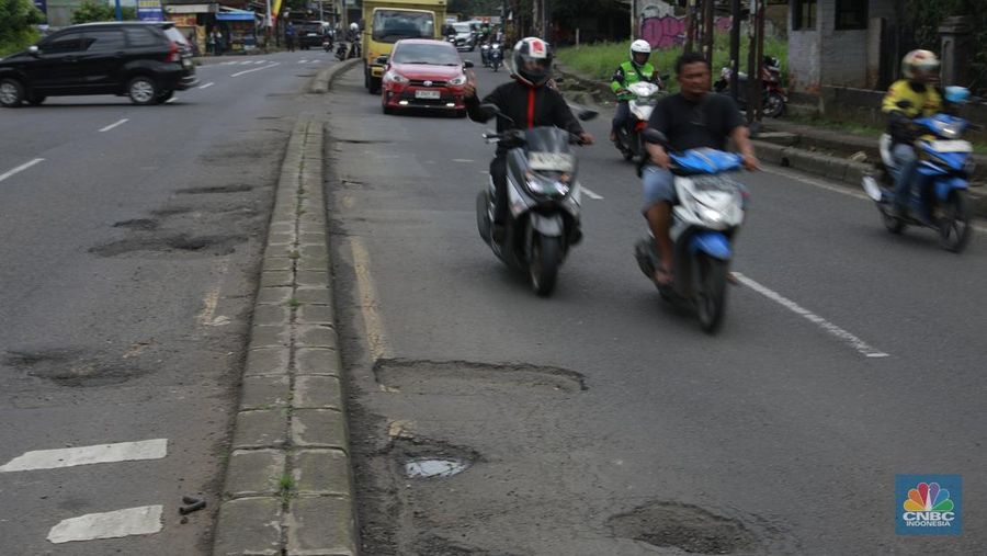 Pengendara mobil roda empat menghindari lobang di Jl raya Moh Toha, Tangeran Selatan, Jumat (6/2/2026). (CNBC Indonesia/Muhammad Sabki)