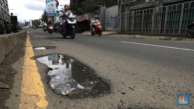 Pengendara mobil roda empat menghindari lobang di Jl raya Moh Toha, Tangeran Selatan, Jumat (6/2/2026). (CNBC Indonesia/Muhammad Sabki)