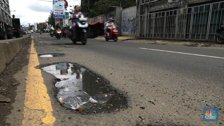 Pengendara mobil roda empat menghindari lobang di Jl raya Moh Toha, Tangeran Selatan, Jumat (6/2/2026). (CNBC Indonesia/Muhammad Sabki)