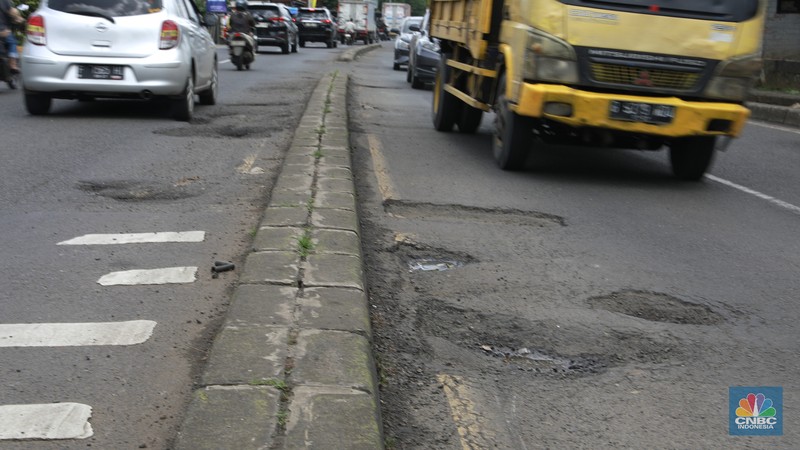 Pengendara mobil roda empat menghindari lobang di Jl raya Moh Toha, Tangeran Selatan, Jumat (6/2/2026). (CNBC Indonesia/Muhammad Sabki)