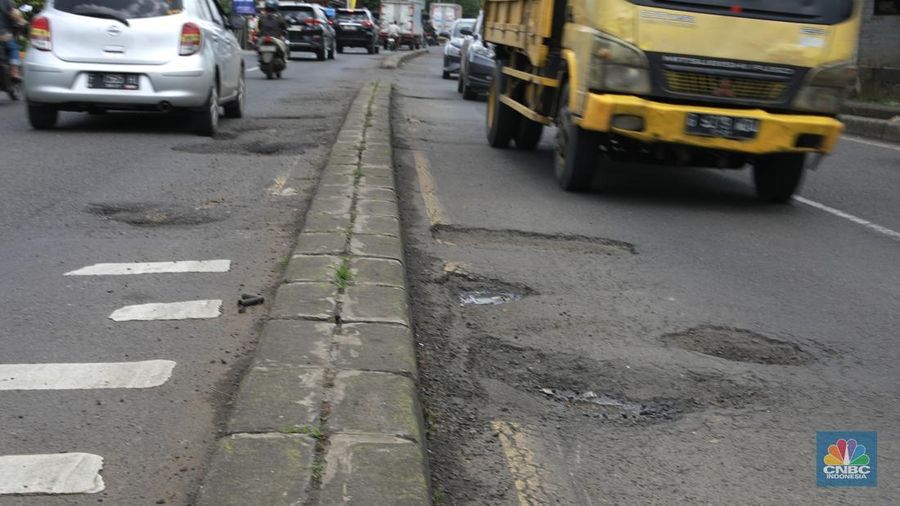 Pengendara mobil roda empat menghindari lobang di Jl raya Moh Toha, Tangeran Selatan, Jumat (6/2/2026). (CNBC Indonesia/Muhammad Sabki)
