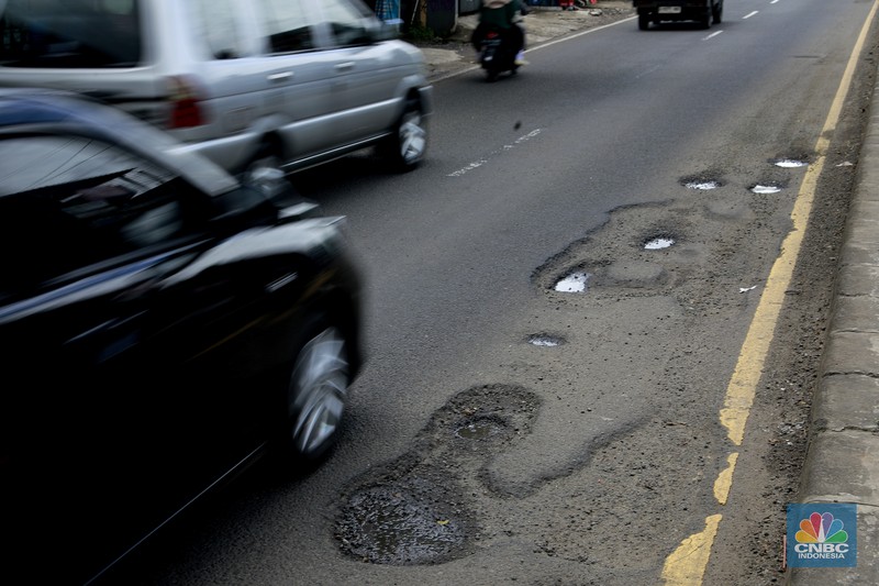 Pengendara mobil roda empat menghindari lobang di Jl raya Moh Toha, Tangeran Selatan, Jumat (6/2/2026). (CNBC Indonesia/Muhammad Sabki)