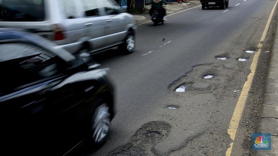 Pengendara mobil roda empat menghindari lobang di Jl raya Moh Toha, Tangeran Selatan, Jumat (6/2/2026). (CNBC Indonesia/Muhammad Sabki)