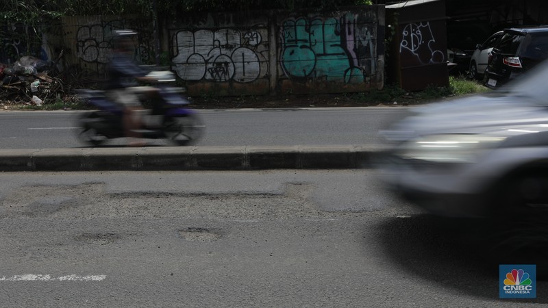 Pengendara mobil roda empat menghindari lobang di Jl raya Moh Toha, Tangeran Selatan, Jumat (6/2/2026). (CNBC Indonesia/Muhammad Sabki)