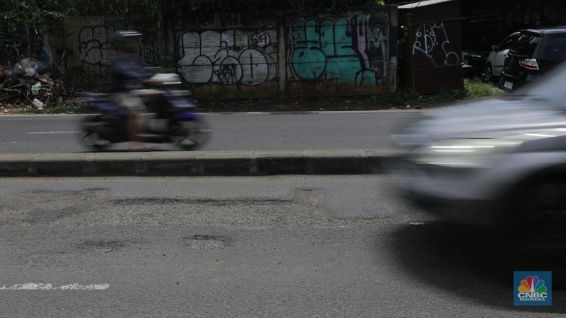 Pengendara mobil roda empat menghindari lobang di Jl raya Moh Toha, Tangeran Selatan, Jumat (6/2/2026). (CNBC Indonesia/Muhammad Sabki)